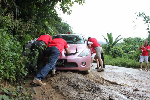 在离开琅勃拉邦的山路上，8号车陷进了凹凸不平的路坑，车队队员帮忙推车。