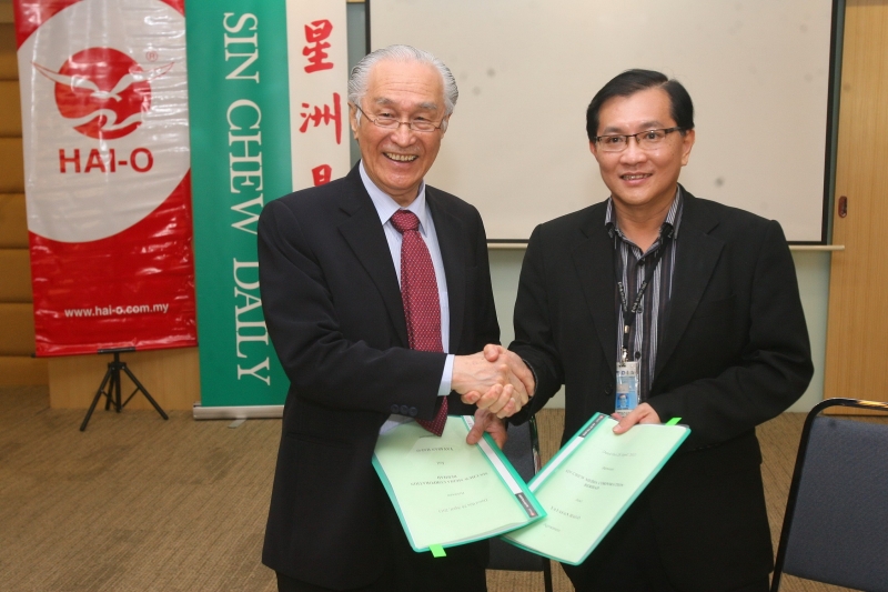 陈凯希（左）及许春签署“爱华教义演2013＂合作协议书後，交换文件，为新一年义演掀开序幕。
