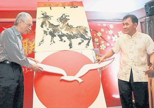 书画名家郭温和（右） 受邀现场挥毫， 为陈凯希送上《祥日羊鸥》水墨画。