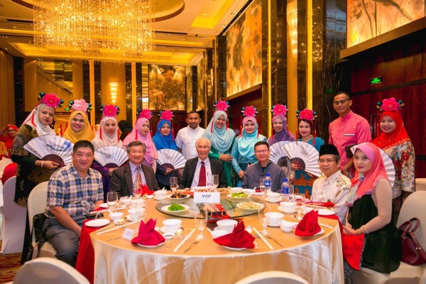 陈凯希（坐左三）与众嘉宾及身穿华人传统服装的直销商们合影。坐左一起为北京外国语大学国际交流与合作处副处长（留学生办公室主任）李冰、陈春福。右一起为拿汀卡亚妮、北京外国语大学马来语研究主任拿督阿旺、谭育麟。